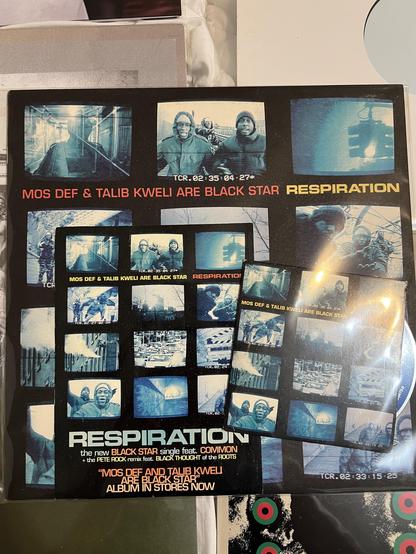 The image features a vinyl record cover AND the CD single for the "Respiration" by Mos Def and Talib Kweli, collectively known as Black Star. The cover includes blue-tinted photographs and text highlighting the collaboration, as well as mentions of featured artists. It also includes a sticker I received when “street teaming” for the label. 