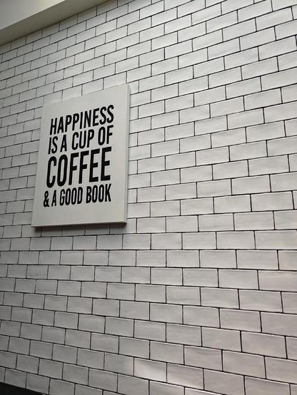 A poster on a wall which says, "Happiness is a cup of coffee & a good book". 