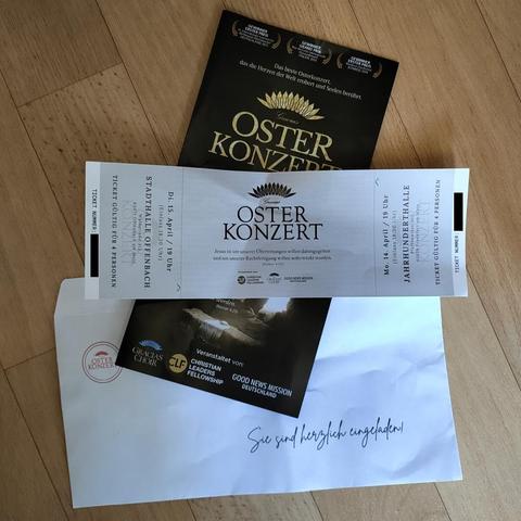 Foto eines Einladungsschreibens für ein "Osterkonzert".
In der obersten Ebene liegt eine Eintrittskarte für Veranstaltungen am 14.04.2025 in der Stadthalle Offenbach und am 15.04.2025 in der Jahrhunderthalle Frankfurt. Darunter liegt ein Flyer. Ausgewiesen als Veranstalter werden:
1. Gracias Choir; 2. Christian Leaders Fellowship; 3. Good News Mission Deutschland.
Darunter liegt ein Briefumschlag mit dem Aufdruck "Sie sind herlich eingeladen!" in einer Handschrift-Schriftart.