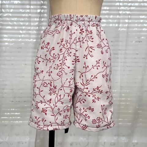 White Boxershorts with red floral pattern on a half scale dressform. A hand is showing where the pockets sit.