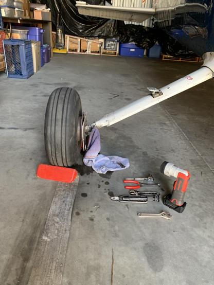 The wheel of an airplane, surrounded by tools and a dirty rag
