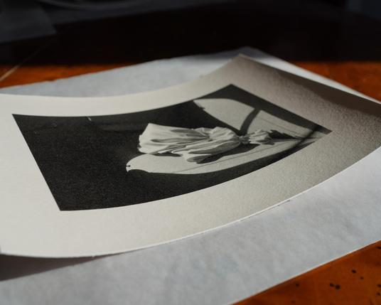 The darkroom print is finished, on the table. Paper is slightly curled.