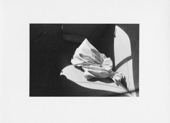 Darkroom print digitalization. The image has big white borders, and two towels are placed on the backseat of a car. Interesting light strikes the towels.