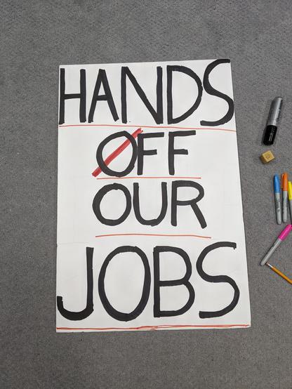 Second sign that reads HANDS OFF OUR JOBS with the O in OFF crossed out in red.