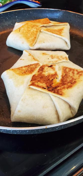 The crunch wrap supreme toasting on the fry pan