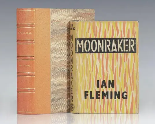 The image features two books by Ian Fleming, prominently displayed against a neutral background. The book on the left has a reddish-brown leather cover with gold embossed lettering that reads "MOONRAKER" and "IAN FLEMING" on the spine. The book on the right has a yellow and orange patterned cover with the title "MOONRAKER" in bold black letters at the top and the author's name "IAN FLEMING" in black letters at the bottom. The spine of the right book also displays the title "MOONRAKER" in vertical orientation. The books are positioned with the left book slightly behind the right, allowing both titles to be visible. The overall appearance suggests these are classic editions of Ian Fleming's works.