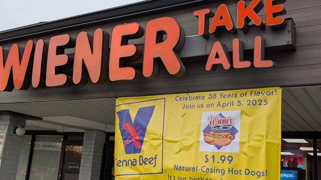 Store front of Weiner Take All in Buffalo Grove, Illinois, USA. A yellow banner is hanging in front that reads: 

Celebrate 38 Years of Flavor! Join Us On April 5, 2025

$1.99 Natural Casing Hot Dogs 