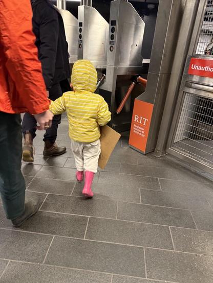 Little girl with pink rain boots carrying her protest sign at the subway turnstile, Grand Central Station 