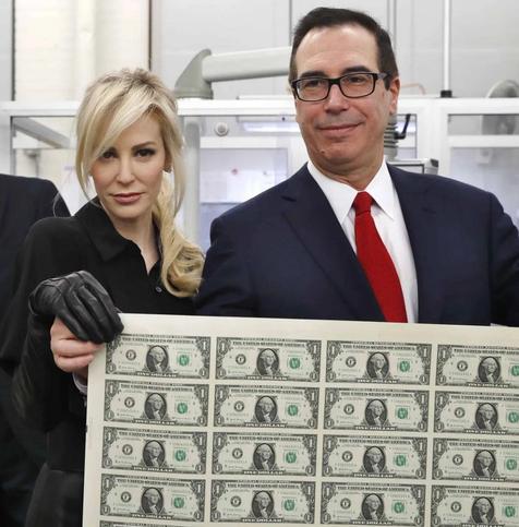 Trump's first Treasury Secretary Steve "No Chin" Mnuchin and his glam wife holding up a sheet of uncut dollar bills.