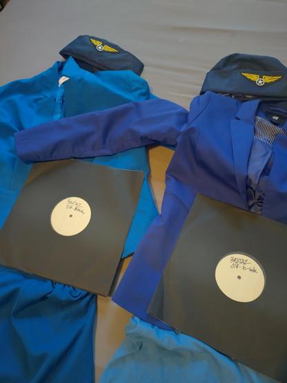 Two dubplates of the upcoming Brutaż releases laid on two flight attendant's uniforms