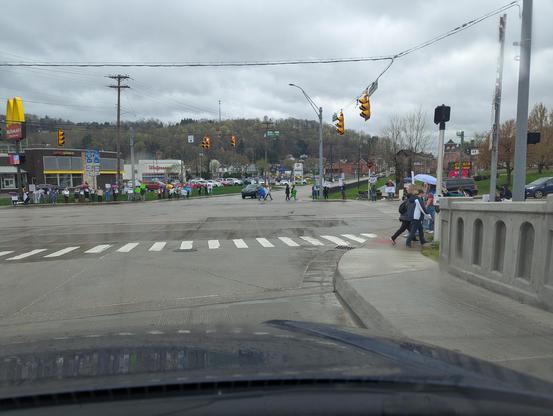 A large crowd of people standing on the corners of an intersection holding signs protesting the Trump administration