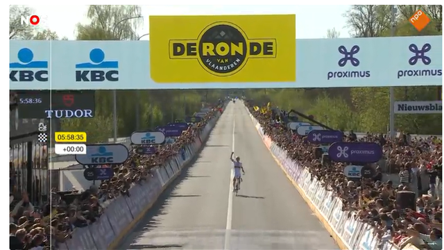 finishfoto (still uit de video) van de Ronde van Vlaanderen, Pogacar fietst met zijn rechterarm in de lucht geheven in zijn eentje over de finish