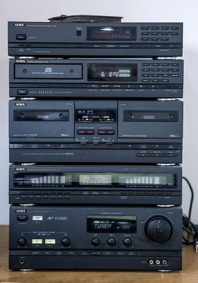 A stack of stereo components, all black with black accents. They are tiny LED lights on some of the controls, but not all.