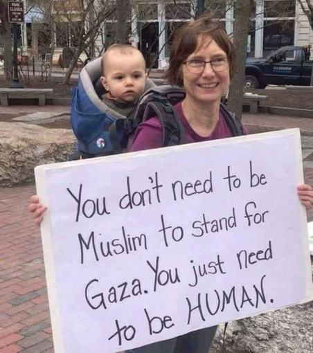 A lady holding a placard saying, "You don't need to be Muslim to stand for Gaza. You just need to be HUMAN"