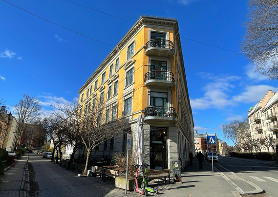 Yellow building from around 1900. Blue sky. Shaped like the flat iron building in NYC