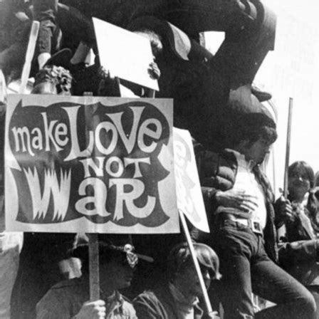 Black and white photograph of protesters at what appears to be an anti-war demonstration, with a person holding a prominent sign that reads 'make LOVE NOT WAR'. Several people are gathered together, some seated on what might be a structure or vehicle, creating a crowded protest scene typical of peace movements from the 1960s-70s era.

Image source 