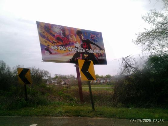 Large billboard displaying "We Are Stronger Together" graphic with Into The Spiderverse characters Miles Morales and Gwen Stacy next to roadside signs.