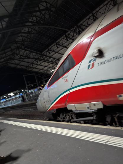 Le nez d'un train ETR610 aux couleurs de trenitalia dans son ancien habillage argenté, rouge et vert. Gare de Lausanne en fond.