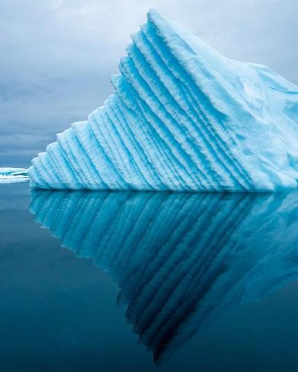Eroding blueish iceberg reflecting in the water.