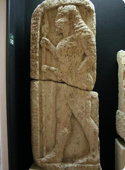 The stele with a warrior in profile and the inscription on the left-hand ledge vertically