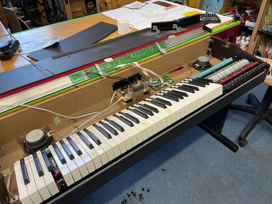 Auf dem Bild befindet sich ein E-Piano. Es ist die Elektronik zu sehen und einige einzelne Schrauben auf dem Boden. 