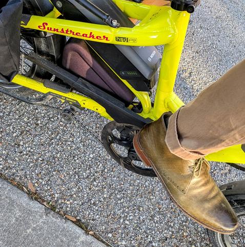 A photo of my right foot on the pedal of a 

yellow Tern HSD cargo bike with its name, Sunstreaker, in red on the seat stay

I'm wearing

olive green short boots under a dark khaki pantleg.