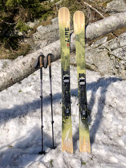My freeride skis and poles lean on a log.
