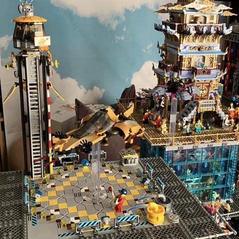 Overview of the landing pad with the D-4QP Interceptor hovering unto land. The pad has a diamond shaped landing zone and a tall thin control tower at one corner, just big enough for one minifig to sit in. 