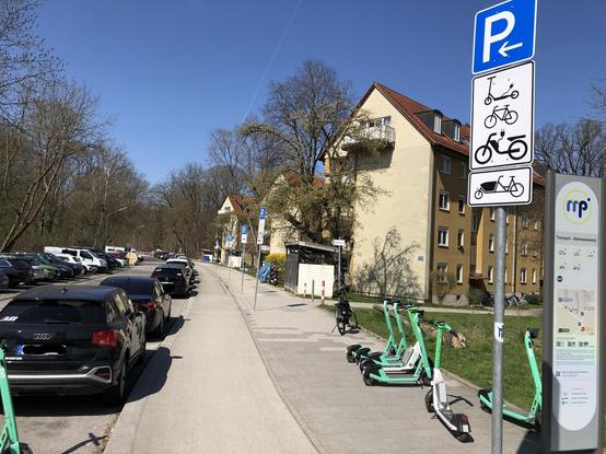 E-Scooter, die zuvor ordnungsgemäß auf einem für sie eingerichteten Parkplatz standen, stehen nun auf dem Gehweg. Stattdessen sind Autos auf dem Parkplatz geparkt.