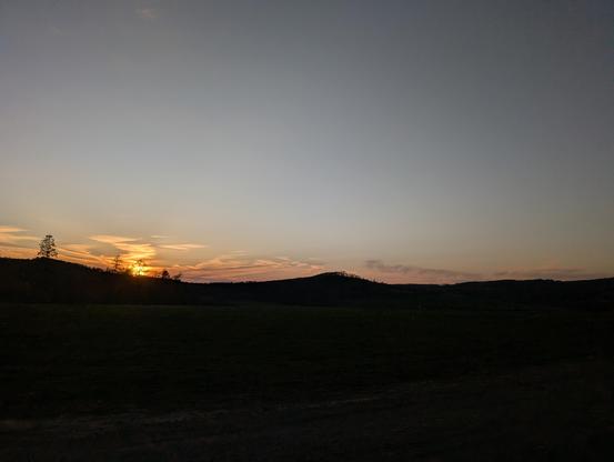 Sonnenuntergang über einer hügeligen Landschaft.