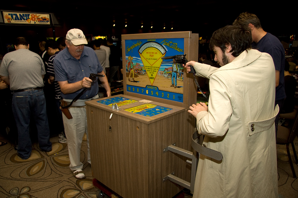 Two people playing Championship Fast Draw in a retro arcade.

https://commons.wikimedia.org/wiki/File:Fast_Draw_arcade_game_1964.jpg