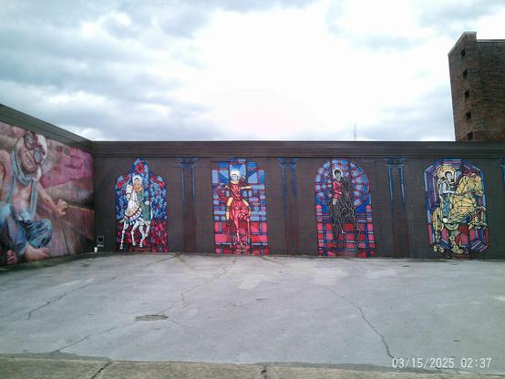 Exterior mural of stained glass-style figures on a building facade, featuring figures on horseback, and other figures in various poses.
