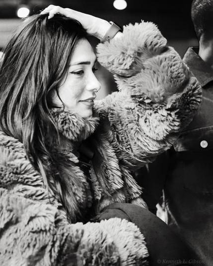 Woman in furry coat with hand on her head.