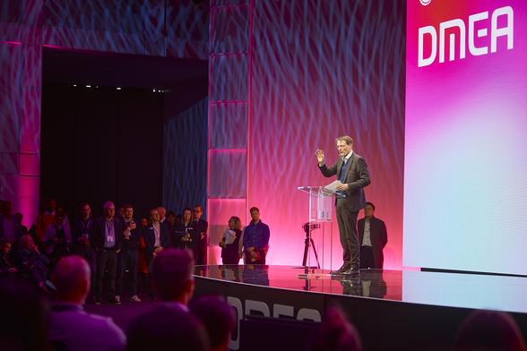 Bundesgesundheitsminister Karl Lauterbach steht auf der Bühne bei der DMEA und hält eine Rede. Im Hintergrund kann man den Schriftzug „DMEA“ lesen, neben und vor der Bühne sieht man das Publikum.