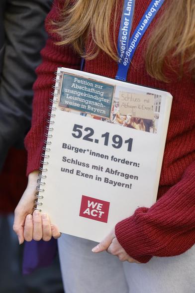 Person hält die WeAct-Petition zur Abschaffung von Exen und Abfragen an Schulen in Bayern.