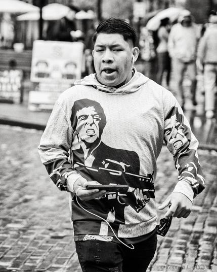Man wearing Scarface shirt running across street.