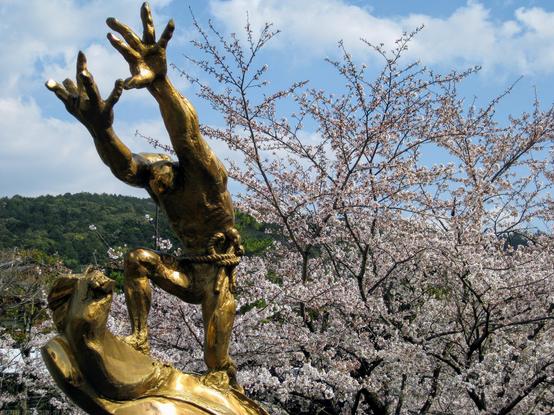 Golden statue surrounded by cherry blossoms outside the Lake Biwa Canal Museum.