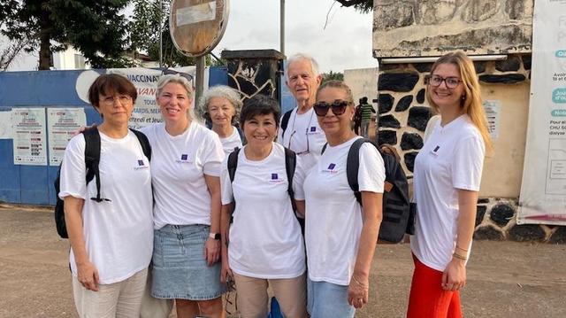 Équipe médicale AP-HM posant en extérieur devant un établissement de santé togolais, souriants et vêtus de t-shirts blancs avec logo du projet ASSILE ASSIME.