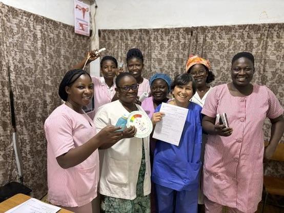 Photo de groupe d’une soignante AP-HM avec un groupe de sages-femmes togolaises, souriantes, tenant des outils pédagogiques et un certificat de formation.