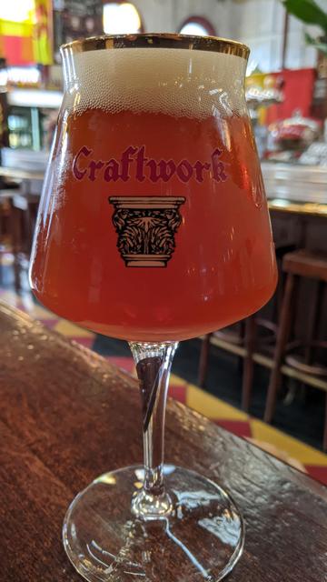 Close-up of a Teku glass of Craftwork's Oude Relic craft beer. Bar visible in the background.