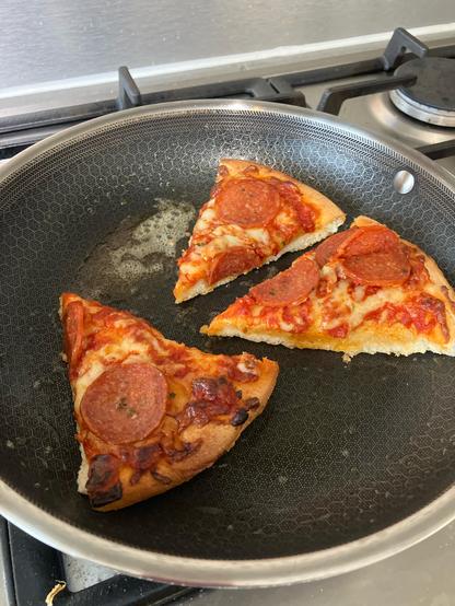 Pizza slices being reheated in a pan