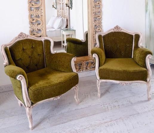 Two green chairs positioned in front of a large mirror, reflecting their vibrant color and surrounding space