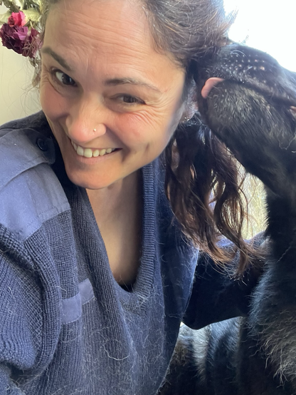 Schäferhund schleckt Frau in blauem Pullover das Ohr ab