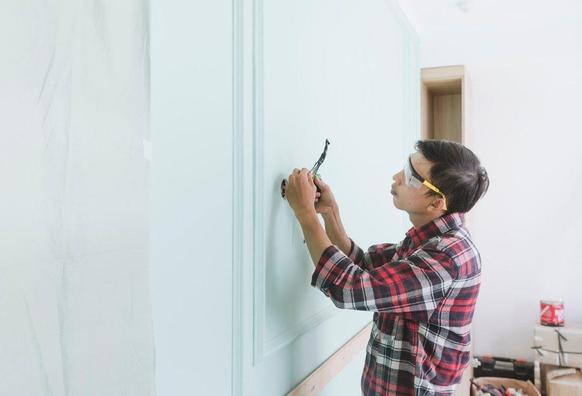  A man diligently working on a wall with a screwdriver, showcasing his concentration and craftsmanship