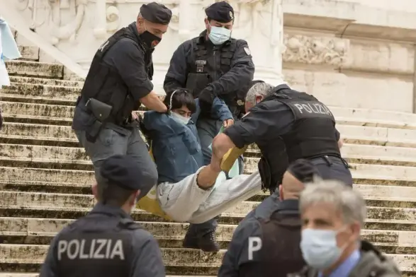 Une action d’Extinction Rebellion Italie, en 2020, sur les marches du Parlement. Trois policiers portent un activiste.