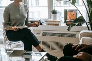 In a living room, a woman engages in conversation with a man, both seated comfortably amidst a welcoming atmosphere