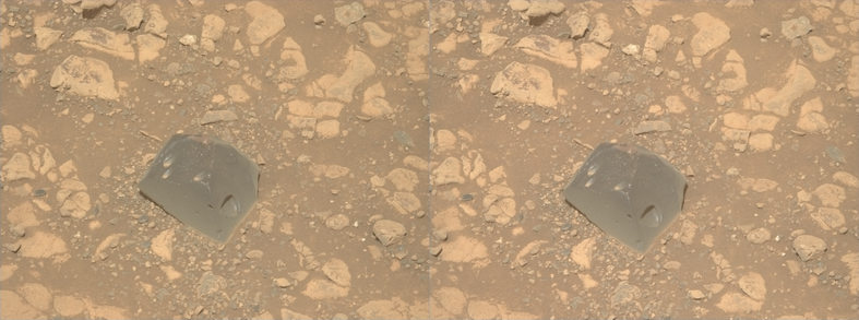 A dual left/right stereoscopic pair of ochre toned photographies capturing a Martian rock. This dual image is intended to be used to obtain a Stereo3D rendition of the scene through parallel viewing, and not cross-eyed viewing. The rock is darker than its surroundings, with a smooth texture, three bright speckles on its top face, and cavities on its sides. 