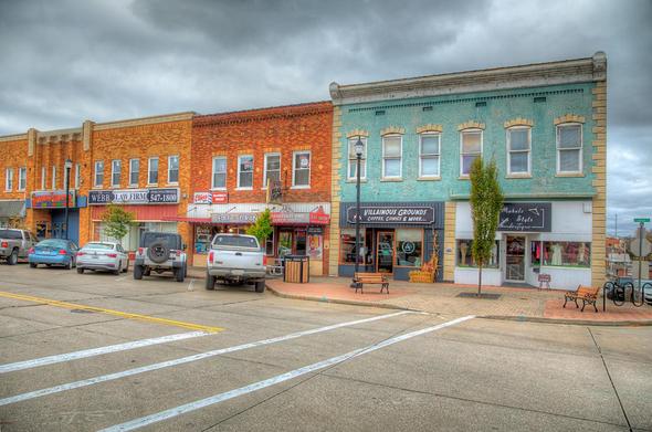 A quaint street scene features a row of colorful, historic buildings with various small businesses and shops. 