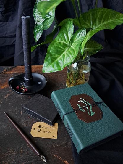 The green covered boon on its side laying on the table to show the stitching on its spine.