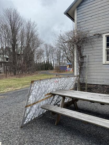A 4x8 metal panel wrapped in protective film rests against our picnic table on a cloudy day 